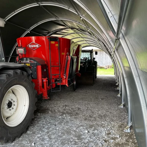 Runbogenhalle mit Maschinen / Traktor im Unterstand von smartlager